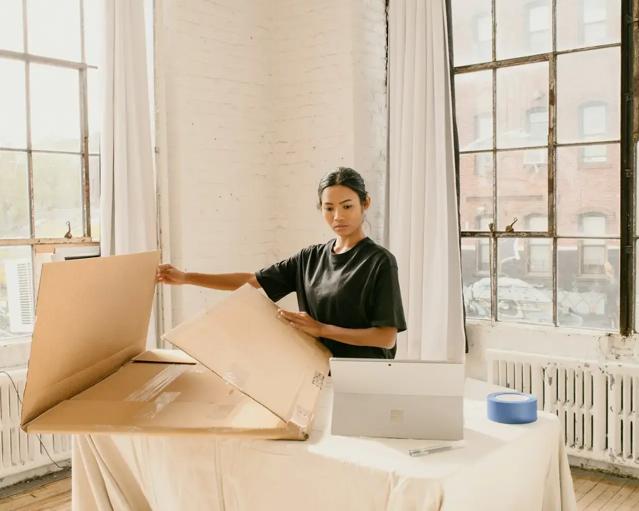 Seller standing beside a packed cardboard box ready for pickup, representing Amazon Self Ship fulfillment