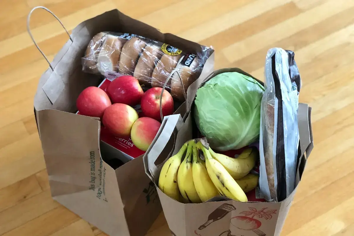 Paper grocery bags with fresh fruit, vegetables and bread, representing quick-commerce grocery orders