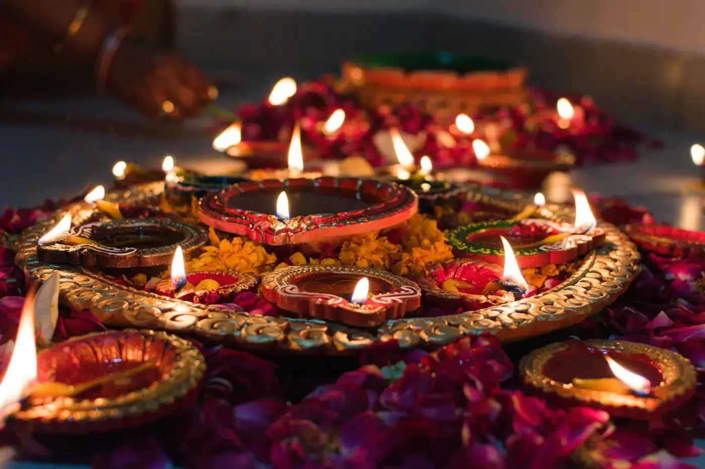 Lit clay diyas on a decorative tray with flower petals for Diwali
