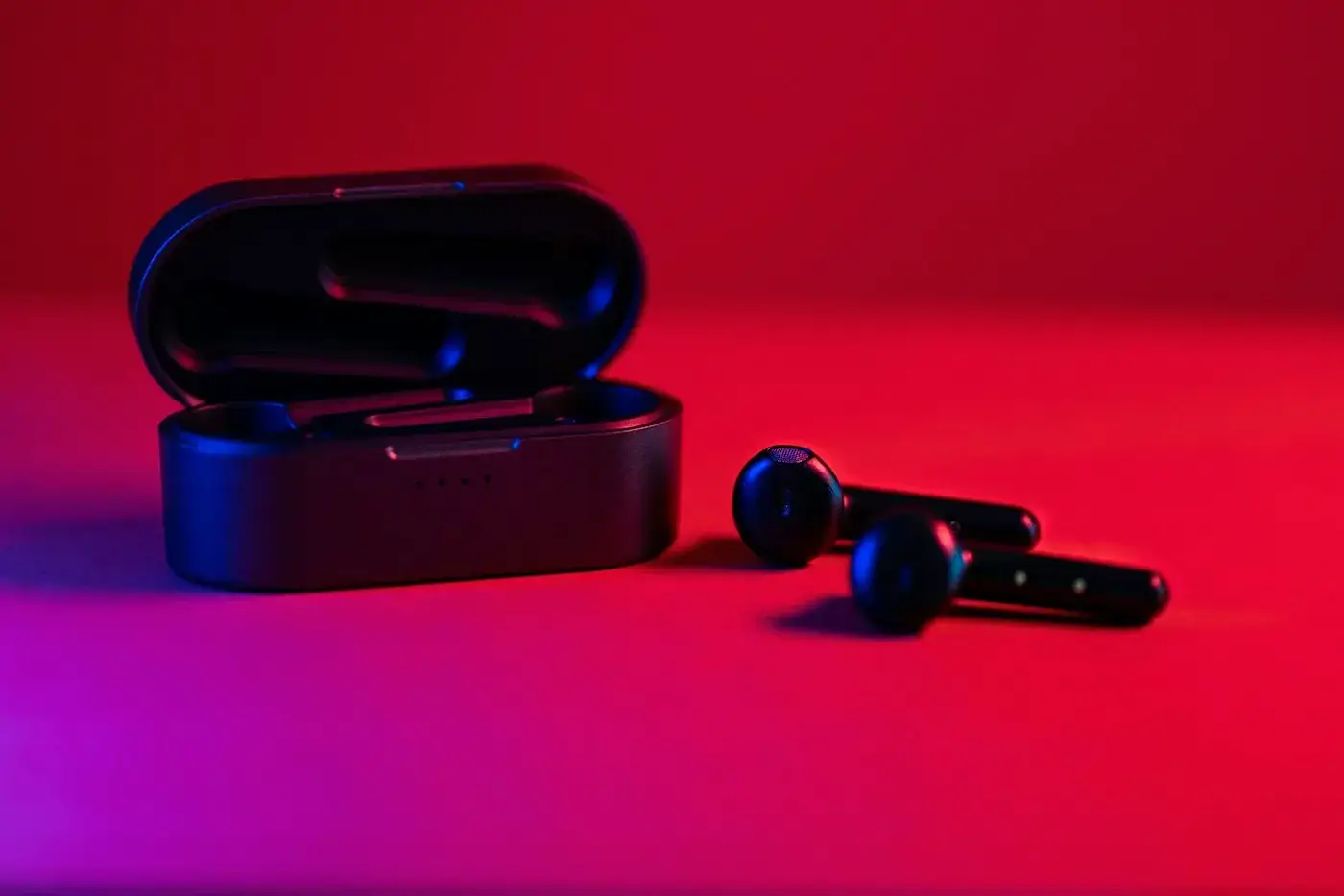 Black true wireless earbuds next to their charging case